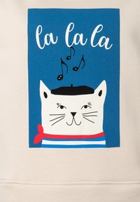 Beige sweatshirt met een blauwe rechthoekige graphic met een cartoon kat in een baret, die een gestreept shirt en een rode sjaal draagt, omringd door noten.