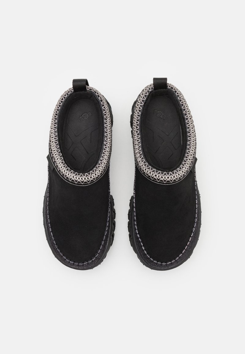 Schwarze Wildleder-Slipper mit einem strukturierten Kragen, elastischem Strickbesatz und einer robusten Gummisohle. Minimalistisches Design mit kontrastierenden Nähten.