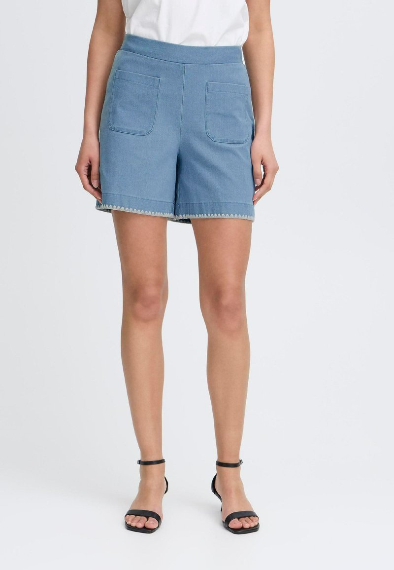 Pantalones cortos de mezclilla en azul claro, con una cintura alta, dos bolsillos frontales y costuras decorativas a lo largo del dobladillo.