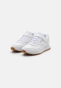 Baskets de sport blanches avec semelles en caoutchouc, fermeture à lacets et bande velcro. Matériau synthétique lisse et doublure rembourrée pour plus de confort.