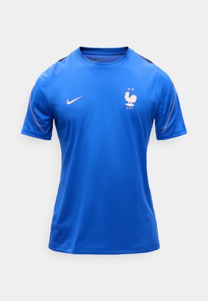 Μπλε αθλητική φανέλα με κοντά μανίκια, με λογότυπο της Nike και έμβλημα της γαλλικής ποδοσφαιρικής ομοσπονδίας με κόκορα και δύο αστέρια στο στήθος.