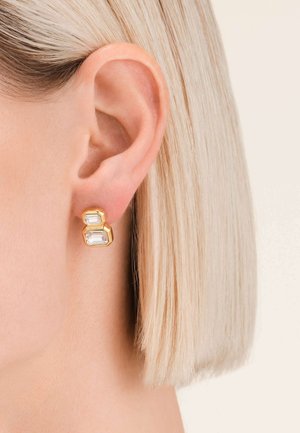 Orecchini geometrici in tono oro con due cristalli trasparenti rettangolari impilati. Il design è moderno, con una finitura lucida e forme angolari.
