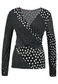 Czarny top na zakładkę, z długimi rękawami i asymetrycznym krojem, ozdobiony białymi groszkami w różnych rozmiarach. Ma gładką fakturę i delikatny połysk.