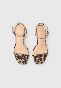 Sandale cu imprimeu de leopard, cu toc mic, vârf deschis, curea pentru glezna și brant bej neted. Superior din material moale cu un model texturat.