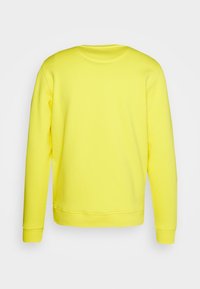 Felpa gialla con maniche lunghe e colletto rotondo. Presenta una texture semplice e liscia e polsini a costina, progettata con un colore uniforme.