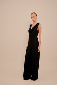 Černý overal bez rukávů s hlubokým výstřihem, širokými nohavicemi a hladkou texturou, zdobený přiléhavým pasem a jemným třpytem.