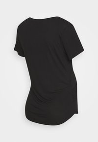 T-shirt preta de mangas curtas, feita de tecido macio. Apresenta um decote redondo e detalhes franzidos nas laterais, com uma bainha ligeiramente curva.