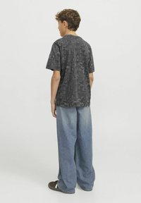 Tumehall, mustriline T-särk lühikeste varrukatega, millele on ühendatud heledamad sinised, laiad teksapüksid ja tumedad jalanõud. Riietus on šiki ja vabalt langeva kujuga.