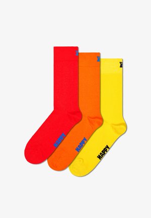 Set of three socks: red, orange, and yellow. Each sock features a ribbed cuff and a blue "HAPPY" graphic on the side. Smooth texture.