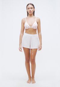 Soutien-gorge blanc avec motif de cœurs rouges, associé à un short beige clair. Tissu doux, coupe décontractée et design simple. Pas d'ornements ni de motifs sur le short.