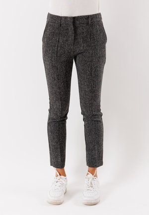 Pantaloni grigi su misura con tessuto texturizzato, taglio slim e lunghezza cropped. Abbinati a sneakers bianche con un design minimalista.