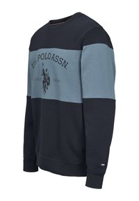 Sötétkék és világoskék panelekkel díszített kerek nyakú pulóver. Fekete grafikus logóval és egy kis zászló díszítéssel az ujjon.