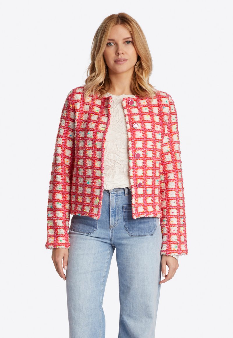 Strukturierte pink-weiße kariertes Jacke mit einer kastenförmigen Silhouette, rundem Ausschnitt und metallischen Knöpfen. Kombiniert mit hellblauen, hochgeschnittenen Jeans.