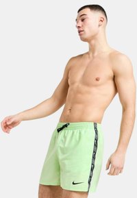 I pantaloni da bagno Nike verdi presentano una vita con cordino, dettagli con logo laterali e una texture leggera e liscia.