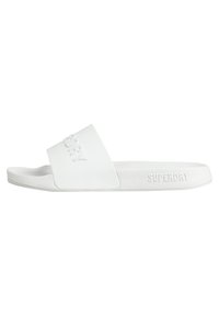Chanclas blancas con una tira texturizada que presenta el logo "SUPERDRY" en relieve. Diseño plano y minimalista con una suela lisa.
