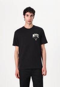 T-shirt en coton noir avec un col rond, des manches courtes et "NYC" imprimé en blanc avec du texte supplémentaire en plus petit sur la poitrine gauche.