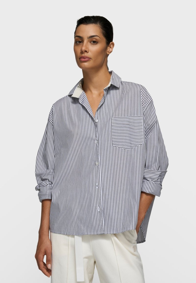 Chemise boutonnée à rayures bleu marine et blanc en coton, avec une poche poitrine et des manches retroussées. Coupe slim, design décontracté avec col.