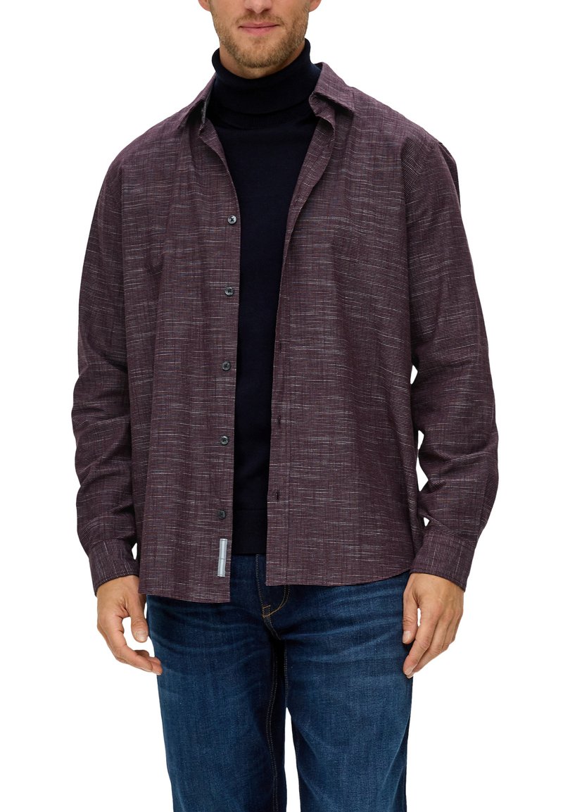 Camisa burdeos texturizada con botones y cuello, combinada con un suéter de cuello alto azul marino y jeans de mezclilla. Presenta bolsillos frontales y un patrón sutil.