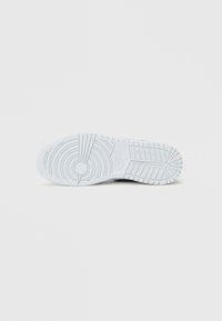 Biała podeszwa tenisówki z teksturowanej gumy, okrągłymi wzorami i centralnym detalem z logo. Posiada rowki zapewniające przyczepność i stabilność.