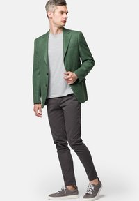 Zielona lniana marynarka z dwoma guzikami, w połączeniu z szarym t-shirtem, ciemnoszarymi slim fit spodniami i szarymi trampkami. Gładka tekstura, dopasowany krój.