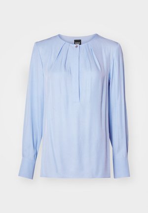 Hele sinine pika varrukaga pluus ümmarguse kaelusega, esipletstega ja nööbiga detailidega. Sile kangas väikese läikega, kehakujuline lõige.