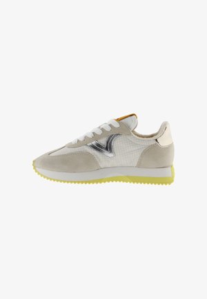 Beige and white sneaker with metallic silver "V" logo, white laces, yellow outsole, and padded collar shown from the outer side.