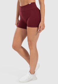 Bordeaux hoge taille shorts gemaakt van rekbaar materiaal, met een zachte textuur en een aansluitend ontwerp. Gecombineerd met witte sportschoenen.