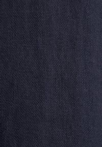 Tessuto di un blu navy scuro con un aspetto intrecciato e testurizzato. La superficie presenta un motivo uniforme e sottile, che appare solido e denso.