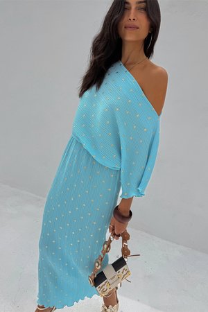 Light blue, off-shoulder dress with vertical stripes and gold dot patterns. Flowing fabric, mid-length, paired with a black and beige handbag.