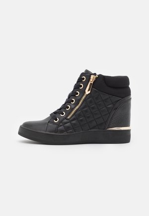 Czarny sneaker na koturnie z pikowanymi bokami, złotym zamkiem błyskawicznym i oczkami, sznurowany z przodu, z wyściełanym kołnierzem wokół kostki.