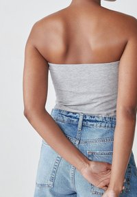 Grå stropløs top parret med højtaljede blå denim shorts. Stoffet er blødt, og shortsene har klassiske syninger og lommer.