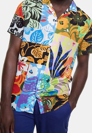 Chemise à manches courtes avec boutons, ornée de grands motifs floraux et de feuilles colorés dans des tons de bleu, orange, vert, noir et jaune.