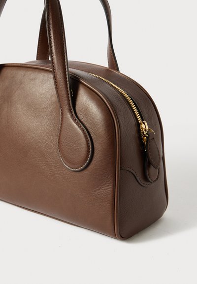 Borsa a mano in pelle marrone con forma arrotondata, cerniera dorata e doppio manico. Presenta una superficie testurizzata e cuciture di accento lungo i bordi.