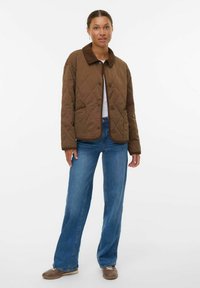 Veste matelassée marron avec un col en velours côtel�é, dotée d'une fermeture à boutons et de deux poches avant, associée à un jean bleu à jambes larges et des chaussures marron.