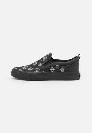 Baskets slip-on noires avec logos et symboles brodés blancs, semelle en caoutchouc, panneaux latéraux élastiques et languette au talon.
