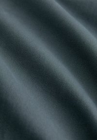 Tessuto con una superficie liscia e leggermente texture in un colore grigio scuro. Il tessuto presenta sottili linee diagonali che creano un motivo a coste.