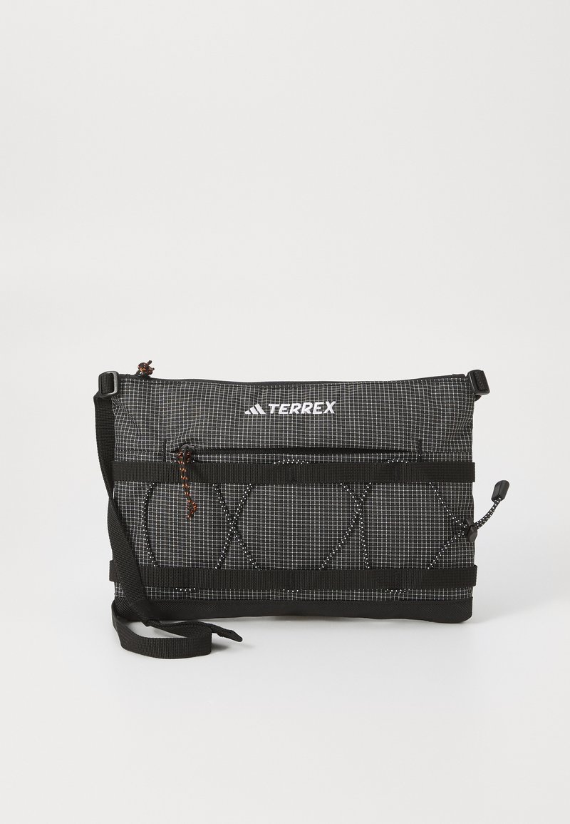 Svart tekstilbag med rutemønster, justerbar stropp, glidelås og frontwebbing. Har "TERREX"-logoen øverst.