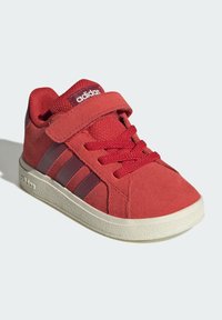 Crvene tenisice za mališane s čičak trakom, vezicama, smešnim prugama sa strane, udobnim okovratnikom i bijelim teksturiranim đonom, brendirane Adidas.