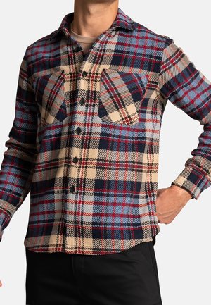 Chemise à carreaux beige, rouge et marine. Présente des boutons, deux poches poitrine et un col classique. Fabriquée à partir d'un tissu texturé.