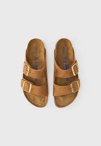 Καφέ δερμάτινα σανδάλια με δύο ρυθμιζόμενα λουριά που διαθέτουν αγκράφες από χρυσό μέταλλο και επενδυμένο πάτο. Αντιολισθητικές υφασμένες σόλες.