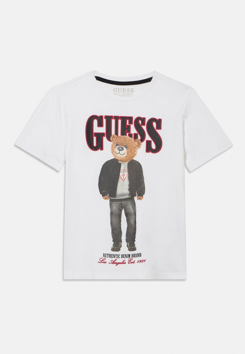 Hvid bomulds-t-shirt med et grafisk print af en bjørn iført sort jakke og jeans, med rød "GUESS"-tekst ovenover og logo nedenunder.