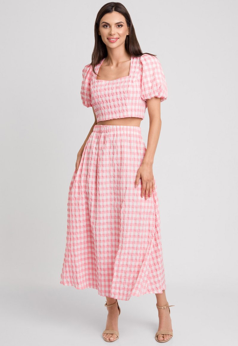 Różowy, w kratkę krótki top z bufiastymi rękawami oraz pasującą długą spódnicą. Materiał wydaje się lekki i ma teksturowane wykończenie, prezentując wzór w gingham.