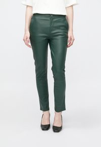 Groene namaakleren broek met een strakke pasvorm, enkelhoogte, ritssluiting aan de voorkant en knoopsluiting. Soepele textuur en minimale details.