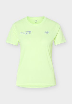 Világoszöld, rövid ujjú sportos póló "tcs 20 26" és New Balance logókkal elöl, futáshoz vagy sportoláshoz tervezve.