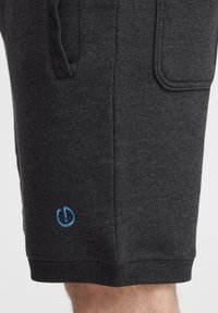 Shorts en coton gris avec une texture douce, dotés d'une poche sur le côté et d'un logo bleu brodé sur l'ourlet.