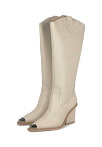 Botas de cuero beige hasta la rodilla con puntas afiladas, tapas metálicas en la punta y un tacón grueso. Presentan costuras y una pestaña para tirar en la parte superior.