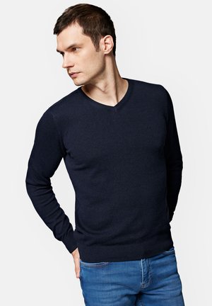 Granatowy sweter z dzianiny z dekoltem w kształcie V, długimi rękawami oraz ściągaczami przy mankietach i dolnym końcu, z małym logo na piersi.