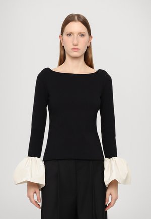 Black long-sleeve top with a wide neckline and voluminous cream-colored fabric at the cuffs. Smooth texture, fitted body, and minimalist design.