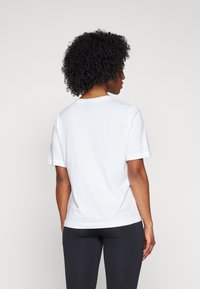 Balta medvilnės t-shirts su laisvu kirpimu, trumpomis rankovėmis ir apvalia iškirpte. Lygus paviršius, tiesus apatinis kraštas nugaros pusėje.