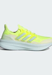 Spilgti dzelteni skriešanas apavi ar teksturētu sietu augšdaļu, trim atstarojošām svītrām un biezu balto skriešanas zoli.